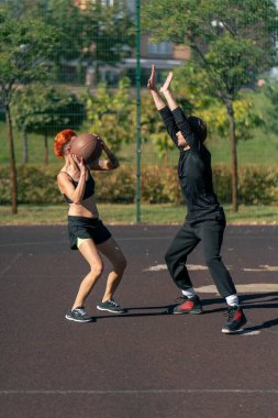 Spor sahasında kısa saçlı, kısa şortlu, sarı tişörtlü basketbol sahası kızı siyah saçlı, basketbol oynayan adamla birlikte.