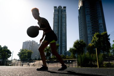 Spor sahası basketbol sahasında kısa saçlı ve siyah tişörtlü kız çeviklik antrenmanına basketbol topu fırlatmak için.