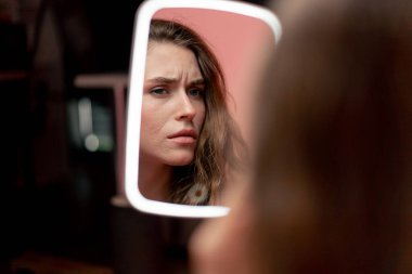 Pembe arka planda bir stüdyonun güzellik çekimi LED ışıklı bir aynaya bakan güzel bir kız cilt değerlendirmesi doğal güzellik kusurlu cilt pozitifliği güzellik salonu