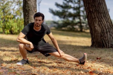 Şehir merkezindeki parkta. Siyah şortlu, esmer ve siyah tişörtlü, sağlıklı yaşam tarzını sürdürmeden önce.