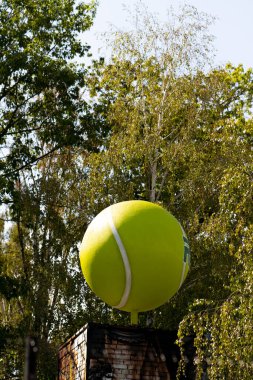 Profesyonel tenis kortuna yakın çekim Ağaçların arasındaki bir binada büyük sahte bir tenis topu