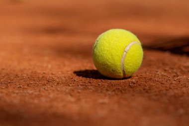 Profesyonel tenis kortunun üzerine kırmızı kil yüzey çizilmiş tenis topları çizilmiş.