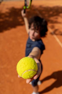 Profesyonel tenis kortunun en iyi vuruşu genç kıvırcık çocuk teknik olarak maçın ilk servisini yapıyor.