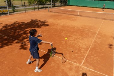 Profesyonel tenis kortunun en iyi vurucusu genç kıvırcık çocuk, sarışın rakip çiftle tenis oynuyor aktif dinlenme antrenmanı yapıyor raketle servis yapıyor.