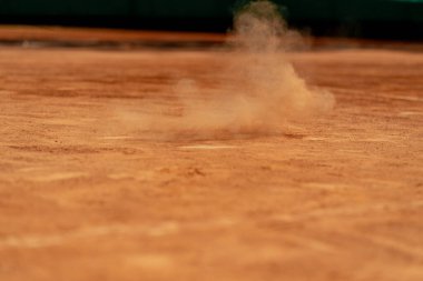 Profesyonel bir tenis kortuna yakın plan kilden bir yüzey üzerinde tenis topu yerden sekip toza dönüşür.