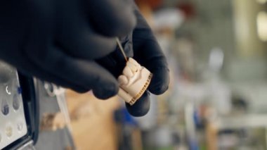 Dikey video, dişçi protozoa kaplaması ve kaplama uzmanı üretimi için profesyonel laboratuarı kapatıyor. Müşterinin dişlerinin altında fırça diş minesi kaplaması ile boya yapıyor.