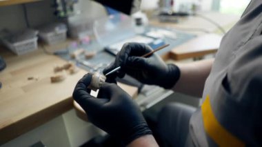 Diş protozoası kaplaması üretimi için profesyonel laboratuarı kapatın ve erkek uzmanlar büyüteçlerle diş şeklini parlatın.