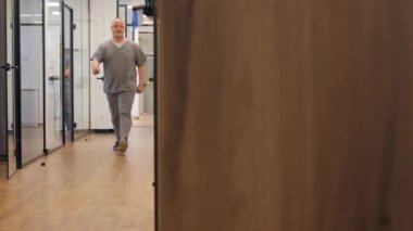 Diş protezleri için koridor profesyonel laboratuarı. Cam kapılar. Koridorda yürüyen modern ofis uzmanı.