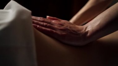 Masaj masasının üstündeki masaj salonunu kapat. Sırtı çıplak bir kız masaj terapistinin yağlı elleriyle arkadan ısınıyor.