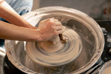 Kil modelleme stüdyosuna yakın genç kız elleri çömlekçi çarkında kil şekillendiriyor eski sanat eserlerini uyguluyor.