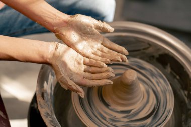 Kil modelleme stüdyosuna yakın genç kız elleri çömlekçi çarkında kil şekillendiriyor eski sanat eserlerini uyguluyor.