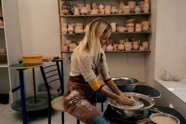 Çamur modelleme stüdyosunda genç kız elleri çömlekçi çarkında kil şekillendiriyor. Eski sanat eseri.