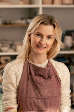 Kil modellik stüdyosuna kapan kilden önlük giyen güzel kız kameraya gülümsüyor ve hafta sonu kirli çamaşırlarına bakıyor.