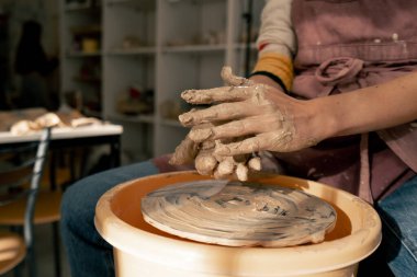 Kil modelleme stüdyosunda genç sarışın bir kız çömlekçi çarklarıyla çalışmayı öğreniyor. Tabakları şekillendiriyor.