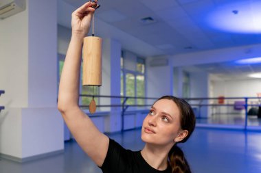 Ruhsal gelişim yüksek lisans sınıfının stüdyosunda mor hasırın üzerinde uzun saçlı yoga kızı lotus pozu otururken el ağacı meditasyonuna bakın.