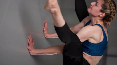 Mavi bluzlu, orta yaşlı bir kız ve parlak bir odada pantolonları olan yoga yüksek lisans sınıfının stüdyosunda çekilen dikey video, kollara vurgu yapıyor.