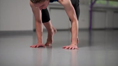 Ruhani gelişim stüdyosunda yoga sınıfında orta yaşlı mavi bluzlu bir kız ve parlak bir odada pantolon giyerek sadece amuda kalkma egzersizi yapar.