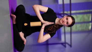 Dikey video, manevi gelişim yüksek lisans sınıfının stüdyosunda mor hasırlı uzun saçlı yoga kızı el ağacı meditasyonunda poz verirken görülüyor.