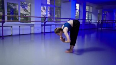 Ruhani gelişim stüdyosunda yoga sınıfında orta yaşlı mavi bluzlu bir kız ve parlak bir odada pantolon giyerek sadece amuda kalkma egzersizi yapar.