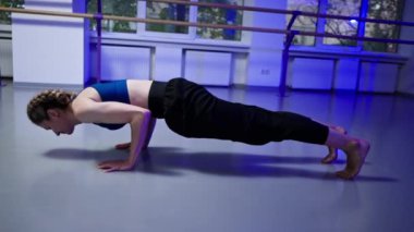 Ruhani gelişim stüdyosunda yoga sınıfında orta yaşlı mavi bluzlu bir kız ve parlak bir odada pantolon giyerek sadece amuda kalkma egzersizi yapar.