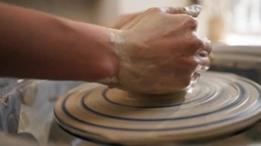 Kil modelleme stüdyosuna yakın genç kız elleri çömlekçi çarkında kil şekillendiriyor eski sanat eserlerini uyguluyor.