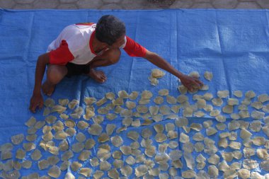 Madiun, Endonezya, 23 Haziran 2023. Büyükbaba kraker kurutuyor. Amaç güneşte kurutmak. Böylece krakerler kızardığında daha da kurur..