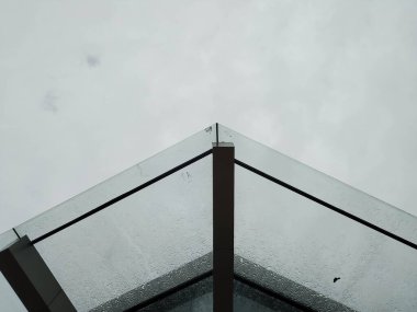 Arka planda bulutlu bir gökyüzü olan camdan bir çatı.