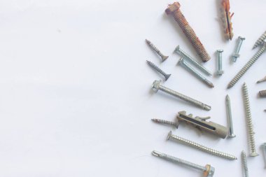 Beyaz arka planda birkaç vida ve çivi var.