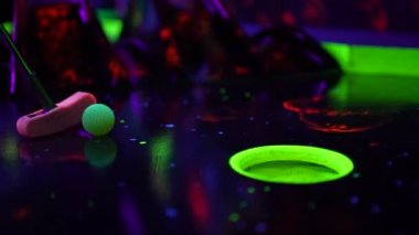 Renkli mini golf sahası ve topun deliğe inişi yakın plan.