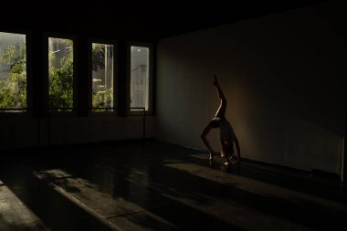 Dans odasında tek başına amuda kalkarak altın ışıklarla pratik yapan bir kız.