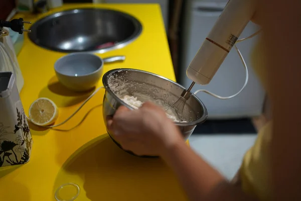 Malzemeleri karıştırıcı ile karıştırırken bir kase tutuyor.