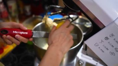 Lemon peel shredding with hands over a mixing bowl