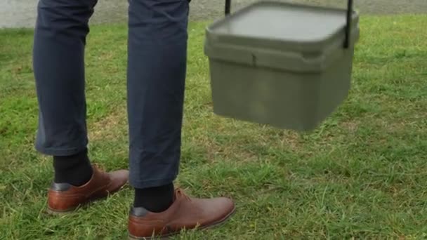 空想の服を着た男が魚の餌の箱を置く — ストック動画