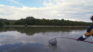 Waiting for a fish to approach the landing net and taking it out