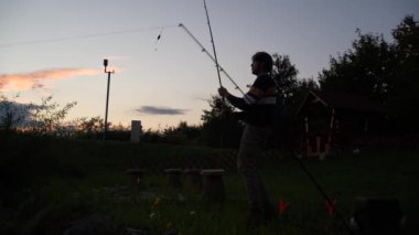 Angler casting out against the sunset while bite on the other rod