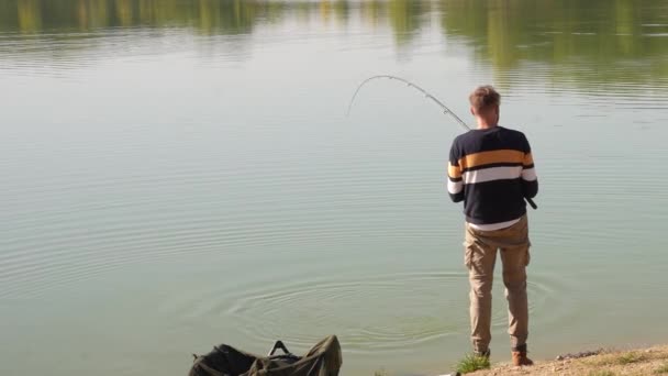 钓鱼的人站在湖边与一条大鱼搏斗 — 图库视频影像