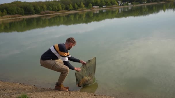 アングラーは湖に戻って大きな魚をリリース — ストック動画
