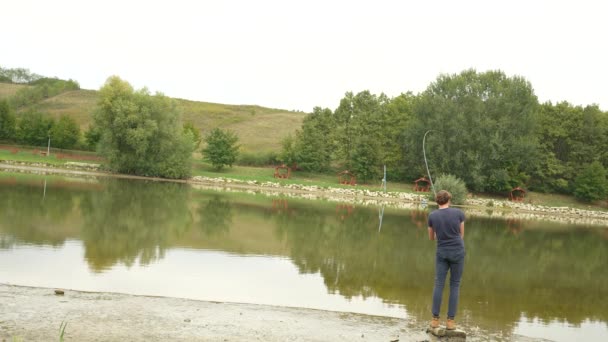 Англер Ловить Рибу Бореться Нею Стоячи Березі Озера — стокове відео