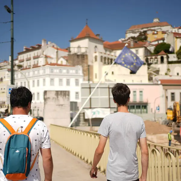 Two people walking down a city with european union flag in front of them