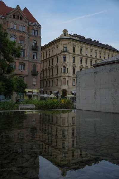 Building and its reflection on the water at a square in the city