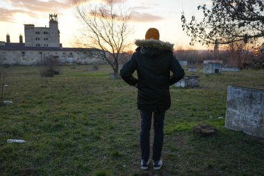 İnce, uzun boylu bir adam kış batımında terk edilmiş bir binaya bakıyor. Yüksek kalite fotoğraf