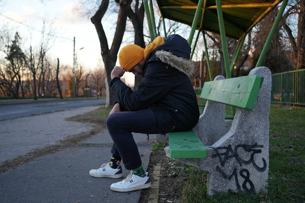 Young guy sitting on a bench depressed thinking. High quality photo