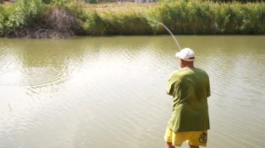 Yaşlı balıkçı göl kenarında balık tutuyor. Yüksek kaliteli FullHD görüntüler