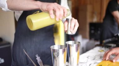 Kokteyl barmeni sallamak ve karıştırmak için bir shot bardağına sarı ananas suyu döküyor. Yüksek kaliteli FullHD görüntüler