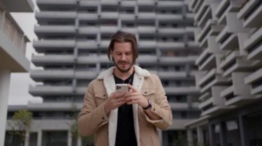 Başarılı, mutlu, gülümseyen, akıllı telefon kullanan profesyonel bir adam. İş adamı cep telefonu kullanıyor, uygulamayı kullanıyor, mesajları zevkli bir gülümsemeyle iletiyor.