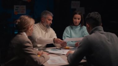 Rüya takım. Kendine güvenen iş adamları, birlikte beyin fırtınası yapıyorlar, akşam toplantısı boyunca modern ofis alanında yeni bir proje üzerinde çalışıyorlar.