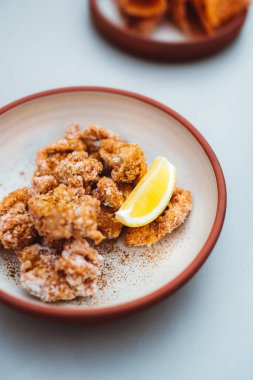 chicken nuggets in a bowl with lemon piece at the restaurant table. Fast food and snacks concept