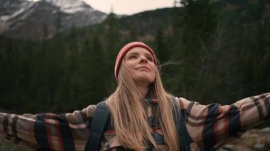 Blonde tourist woman gazing at mountains and lake. Caucasian girl with hat and backpack looking at scenic views alone. Travelling concept