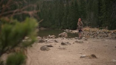 Beautiful woman in yellow hat walking in forest, looks straight, inhale and breathe in fresh after rain air. Travel adventure tourism concept. Road trip wanderlust mood