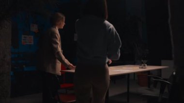 Brainstorming team sitting table gathering in evening office. Diverse colleagues appreciate the presentation and discussing emotionally at contemporary office